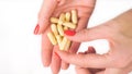 Woman`s hand gives yellow capsule pills