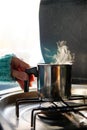 woman\'s hand grabbing a saucepan with boiling drink in a camper van. camping in winter