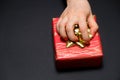 A woman's hand grabs a gift box by a bow on a black background with a place for text. Royalty Free Stock Photo