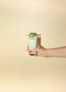 Woman's hand hold a broccoli smoothie in a glass. Minimal healthy composition