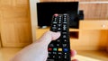 Woman's hand hold remote control and push button to switch on TV for watching television on holiday for relaxion Royalty Free Stock Photo