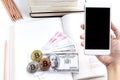 A woman`s hand hold a smartphone with Banknote and bitcoin on th Royalty Free Stock Photo