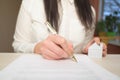 Woman`s hand holding ballpoint pen writing on agreement contract  paper sheet, applying for mortgage loan, filling in document tem Royalty Free Stock Photo