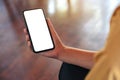 A woman`s hand holding black mobile phone with blank white desktop screen Royalty Free Stock Photo