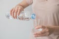 Woman`s hand holding a bottle of water Pouring water into a glass Royalty Free Stock Photo