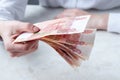 A woman`s hand is holding a bundle of large five thousand rubles bills over the table