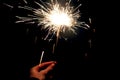 Woman`s hand holding burning Sparkler in hand in the dark on black background. Celebration concept Royalty Free Stock Photo