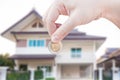 Woman`s Hand holding Coin on house background Royalty Free Stock Photo