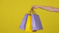 A woman& x27;s hand holding colorful paper shopping bags on a yellow background close up. Black friday sale concept. Royalty Free Stock Photo