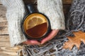 Woman`s hand holding cup of tea with lemon on a cold day. Wooden table. Top view. Concept autumn Royalty Free Stock Photo