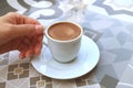 Woman`s Hand Holding a Cup of Turkish Coffee Served on a Moorish Pattern Table Royalty Free Stock Photo