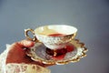Woman`s hand holding delicate tea cup and saucier full of red liquid Royalty Free Stock Photo