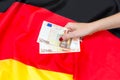 Woman's hand holding euro bills against german flag Royalty Free Stock Photo