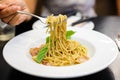 Woman`s hand holding fork for eating spaghetti spicy bacon & ham. Royalty Free Stock Photo