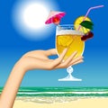 Woman`s hand holding a fruit cocktail against the sea beach