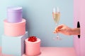 Woman`s hand holding a glass of white wine on blue and pink background Royalty Free Stock Photo