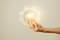 Woman`s hand holding glowing light bulb with energy resources icons. Ecological friendly and sustainable environment concept