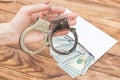 Woman`s hand holding handcuffs over table with money in envelope Royalty Free Stock Photo
