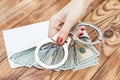 Woman`s hand holding handcuffs over table with money in envelope Royalty Free Stock Photo