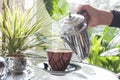 Woman`s Hand Holding Hot Teapot In Morning Sunlight, Retro Colors, A Window Through Which The Sun Shines