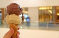 Woman`s hand holding ice cream cone with two scoops of chocolate and peanut butter ice