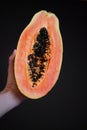 woman's hand holding juicy papaya halves on black background, tropical fruit close-up Royalty Free Stock Photo