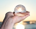 Woman`s hand holding Lemurian Clear Quartz Sphere in a scallop shell at the sunrise Royalty Free Stock Photo