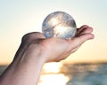 Woman`s hand holding Lemurian Clear Quartz Sphere at the sunrise Royalty Free Stock Photo