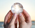 Woman`s hand holding Lemurian Clear Quartz Sphere at the sunrise Royalty Free Stock Photo