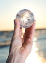 Woman`s hand holding Lemurian Clear Quartz Sphere at the sunrise