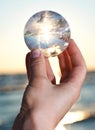 Woman`s hand holding Lemurian Clear Quartz Sphere at the sunrise Royalty Free Stock Photo