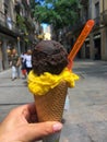 Woman`s hand holding melting chocolate and fruit ice cream waffle cone, street life Royalty Free Stock Photo