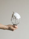 Woman`s hand holding a mixer whisk with whipped egg whites Royalty Free Stock Photo