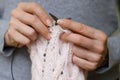 Woman`s hand holding needles and knitting pink clothing detail