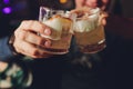 Woman`s hand holding old fashioned glass with cold cocktail against blurred night club background. Royalty Free Stock Photo