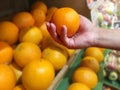 Woman`s hand holding orange from the shelf in the supermarket. Royalty Free Stock Photo