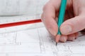 Woman`s hand holding pencil and architectural plans