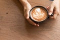 Woman`s hand is Holding Piccolo Latte art in a cup topping beautiful heart art from milk