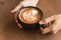 Woman`s hand is Holding Piccolo Latte art in a cup topping beautiful heart art from milk