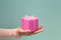 Woman`s hand holding pink gift box in polka dots