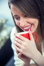 Woman`s hand holding a red cup of coffee. With a beautiful winte Royalty Free Stock Photo