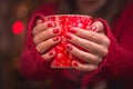 Woman`s hand holding a red cup of coffee. With a beautiful winter manicure. Royalty Free Stock Photo