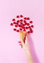 Woman`s hand holding a scoop of ice-cream. Heart shape drops all around imitating ice-cream. Royalty Free Stock Photo