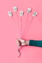 A woman`s hand holding several tea bags as if they were balloons over pink background Royalty Free Stock Photo