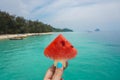 A woman's hand holding a slice of ripe watermelon in hand against the background of the blue sea Royalty Free Stock Photo