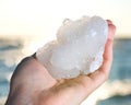 Woman`s hand holding spirit quartz cluster from South Africa in front of the lake