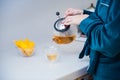 Woman`s hand holding transparent kettle while pouring tea into a transparent mug. Flower tea brewed in a glass teapot with pieces Royalty Free Stock Photo