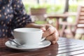 Woman`s hand holding a white coffee cup in cafe blurred background  with morning sunlight Royalty Free Stock Photo