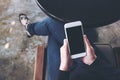 A woman`s hand holding white mobile phone with blank desktop screen on thigh in cafe Royalty Free Stock Photo