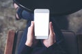 A woman`s hand holding white mobile phone with blank desktop screen on thigh in cafe Royalty Free Stock Photo